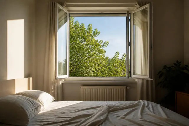 Weit geöffnetes Schlafzimmerfenster beim morgendlichen Lüften